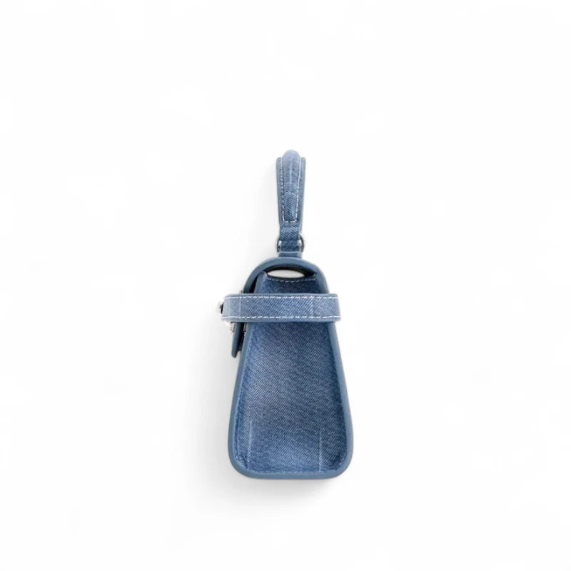 Bolsa feminina estruturada pequena em jeans azul, vista lateral mostrando alça superior