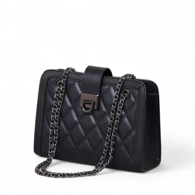 Bolsa feminina preta Matelassê Helena vista lateral, couro de alta qualidade e corrente metálica.