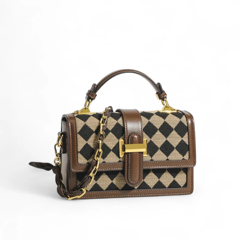 Bolsa transversal feminina Isabela marrom com estampa de losangos pretos e alça de corrente dourada.