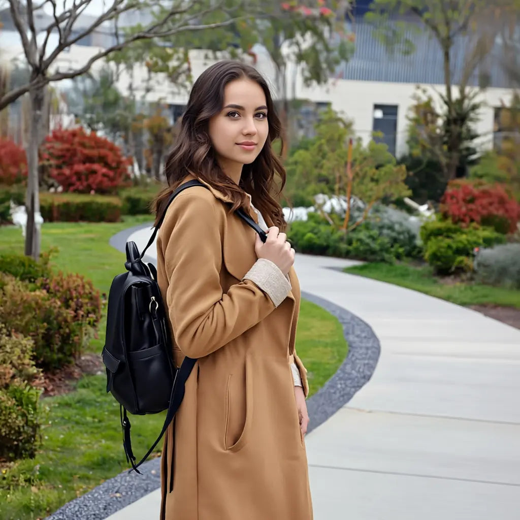 Mulher com mochila feminina preta em look elegante, destacando design minimalista e acabamento em couro sintético. Ideal para quem busca estilo e praticidade no dia a dia.