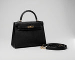 Bolsa Catarina feminina preta estruturada em material sintético com fechamento dourado e alça transversal ao lado