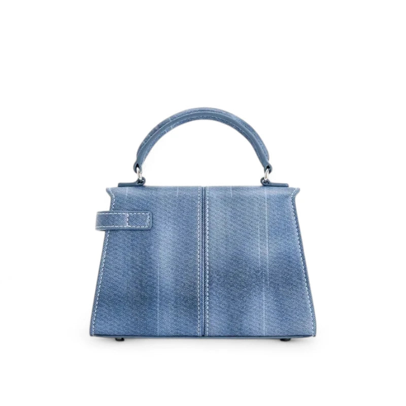 Bolsa feminina estruturada pequena em jeans azul, vista traseira mostrando alça superior