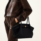 Mulher usando a bolsa feminina preta, combinada com jaqueta de couro marrom e calça de veludo