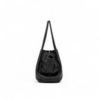 Vista lateral da bolsa feminina em couro sintetico preto, destacando formato estruturado e alças longas