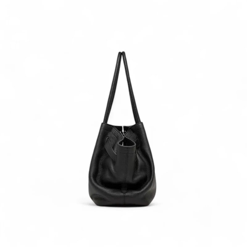 Vista lateral da bolsa feminina em couro sintetico preto, destacando formato estruturado e alças longas