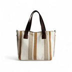 Bolsa feminina transversal em tons neutros com listras em bege, marrom e creme. Design elegante e versátil para looks casuais ou trabalhistas.
