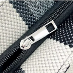 Detalhe do zíper metálico resistente da bolsa feminina listrada, com acabamento elegante e durável. Ideal para manter seus pertences seguros e organizados