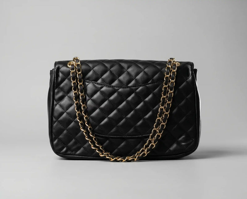 Vista traseira da bolsa Paris preta acolchoada, detalhando o design clássico com bolso externo discreto e alça em corrente dourada