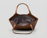 Detalhe do interior de bolsa feminina Velucci com forro em tecido acetinado cinza, bolso interno com zíper e amplo espaço organizacional.