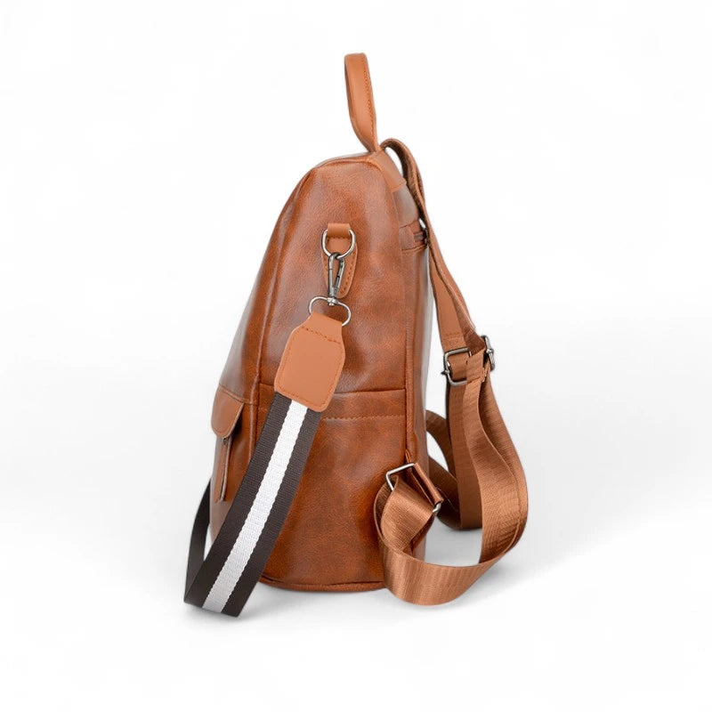 Lado da mochila feminina marrom com alça transversal removível e bolso externo. Detalhes funcionais para armazenar itens com facilidade.